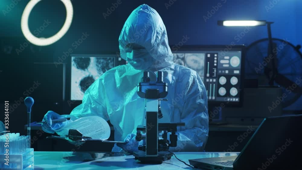 Scientist in protection suit and masks working in research lab using laboratory equipment: microscopes, test tubes. Coronavirus SARS-CoV-2 hazard, pharmaceutical discovery, bacteriology and virology. Scientist in protection suit and masks working in research lab using laboratory equipment: microscopes, test tubes. Coronavirus SARS-CoV-2 hazard, pharmaceutical discovery, bacteriology and virology.