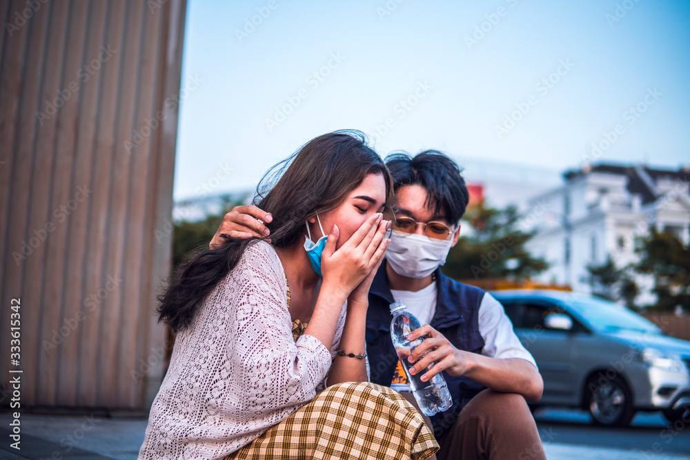 Unhealthy Asian woman sneezing and cough with protective face mask while man trying to help