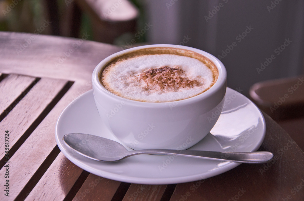 White ceramic cup of coffee and small dish on brown floor White ceramic cup of coffee and small dish on brown floor