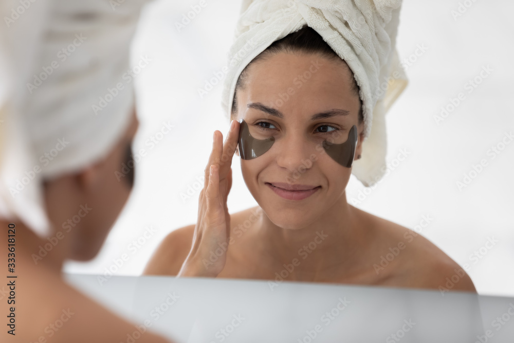Close up face of woman reflected in mirror after morning shower she applied eyes hydrogel patches to reduce puffiness remove dark circles. Helpful beauty treatment, personal care and hygiene concept Close up face of woman reflected in mirror after morning shower she applied eyes hydrogel patches to reduce puffiness remove dark circles. Helpful beauty treatment, personal care and hygiene concept