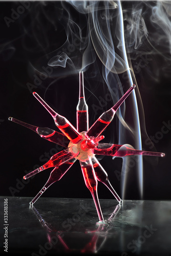 Glass ampoules with a red medicine coronavirus treatment glued together in two conglomerate shape on a glass laboratory shelf on a back bckground photo