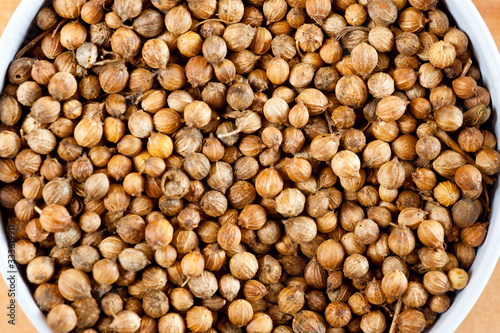 Coriander grains shot large on a wooden background. Background for spices and cuisine.