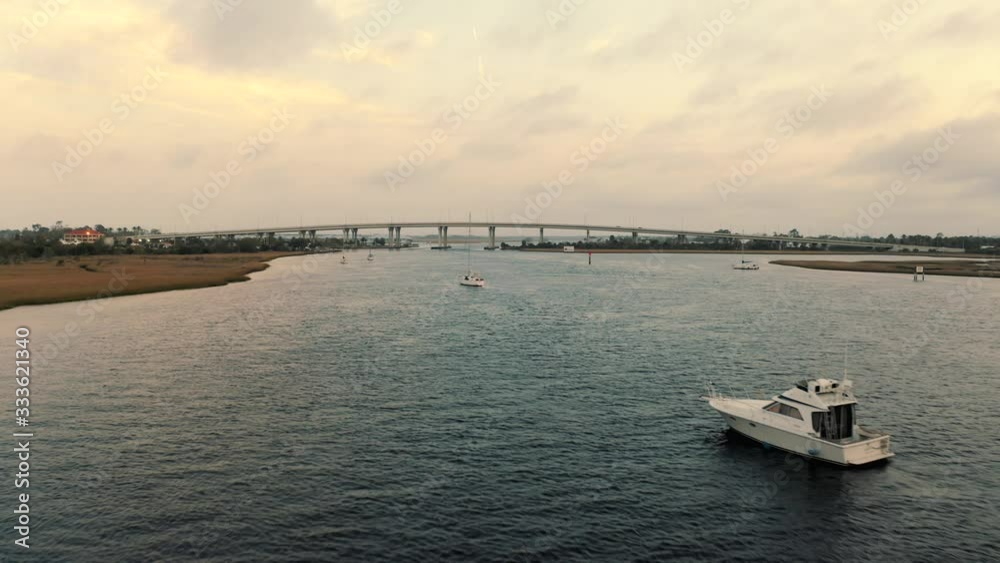 A drone flies over still boats in a calm intercostal water way A drone flies over still boats in a calm intercostal water way