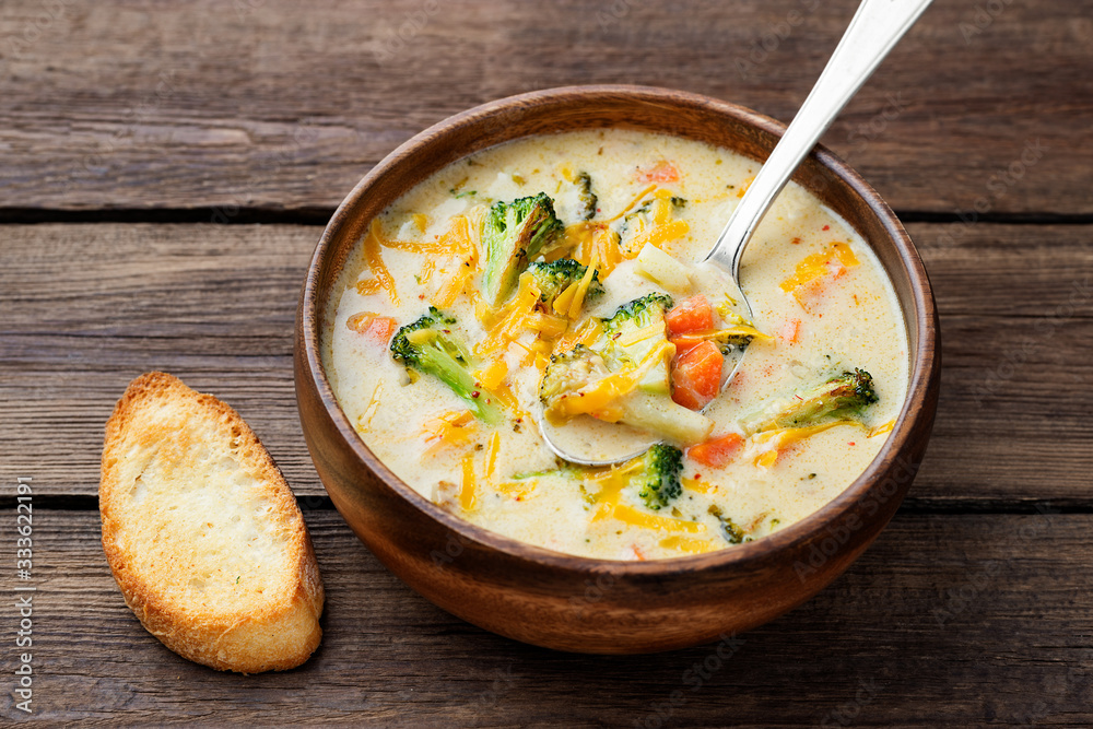 Wooden bowl of creamy broccoli cheddar cheese soup with toasted bread Wooden bowl of creamy broccoli cheddar cheese soup with toasted bread