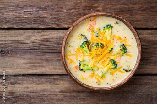 Wooden bowl of creamy broccoli cheddar cheese soup top wiev