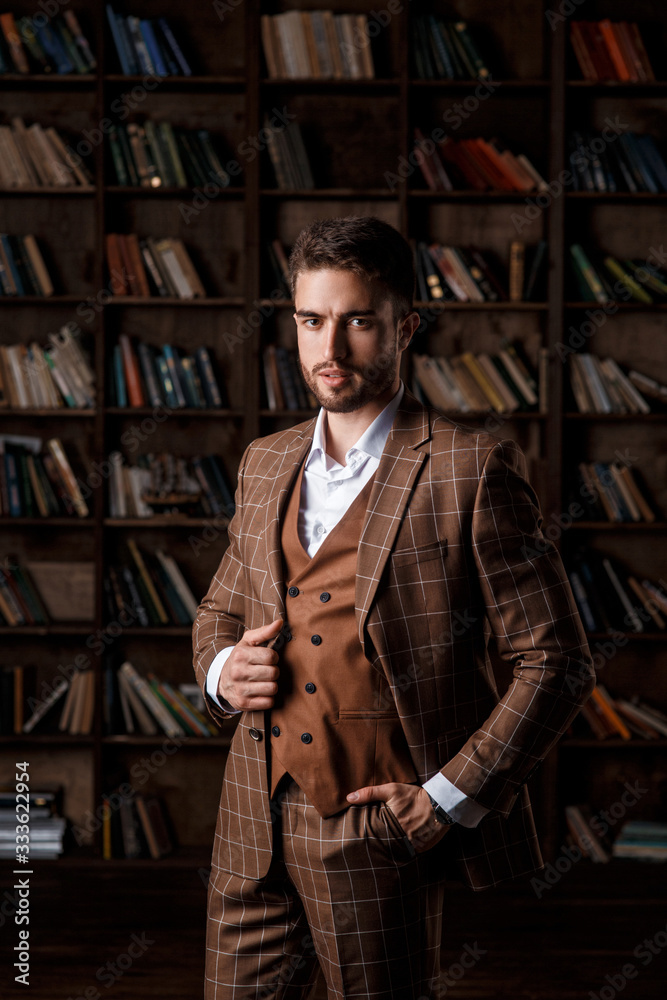portrait of a young bearded businessman in a brown suit against the background of the library portrait of a young bearded businessman in a brown suit against the background of the library