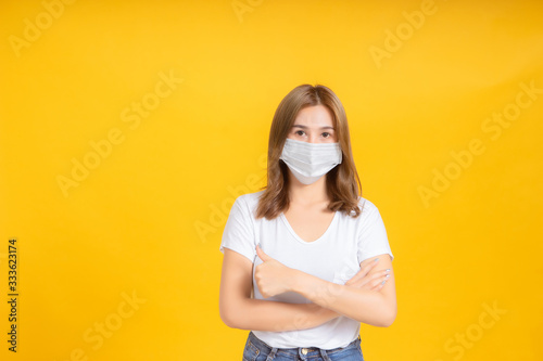 Asian women crossed arms thumbs up wear correct masks to protect against germs from coronavirus, covid-19, pm2.5 dust and prevent infections on a yellow background, healthy concept.