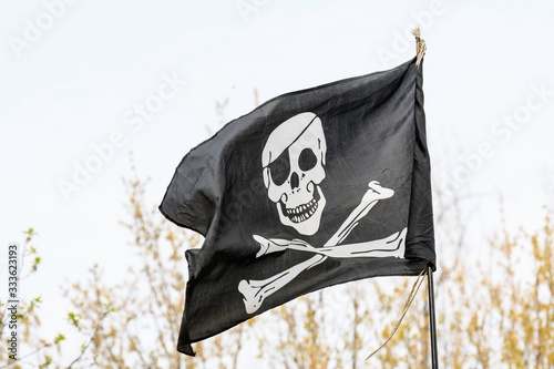 Generic pirate flag blowing in the wind towards cloudy grey sky in a rainy day  photo