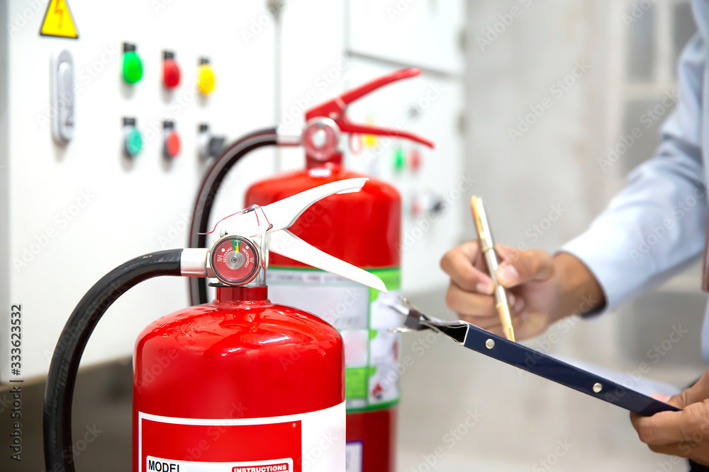 Engineer are checking and inspection a red fire extinguishers in the fire control room for safety prevention and fire training.