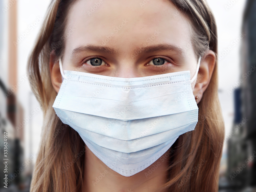 Portrait of a young girl in a medical mask. Protection from viruses and coronaviruses. The flu and SARS epidemic. Background with close-up.