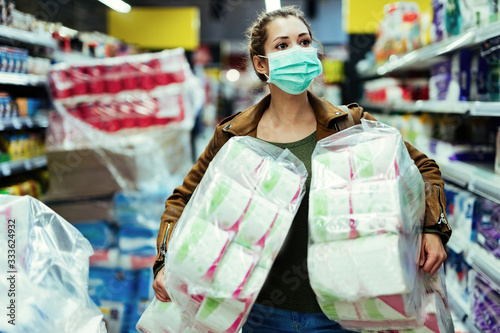 Woman with face mask buying toilet paper in supermarket during virus epidemic.