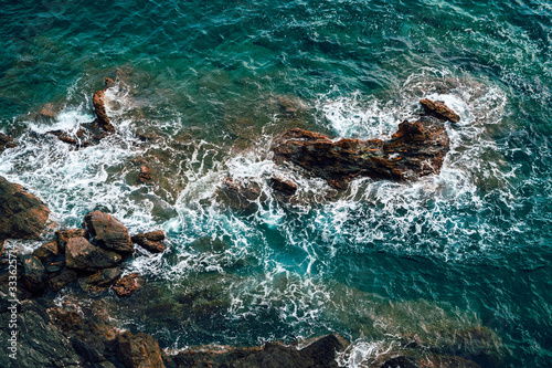 Aerial view of deep blue Mediterranean sea waves crashing against rocky cliffs.