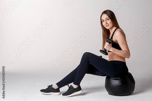 Strong muscular girl working out with dumbbells. Photo of attractive sporty girl isolated on white background. Strength and motivation