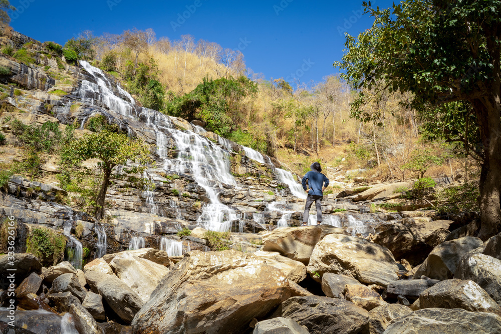 A man standing in front of Mae Klang waterfall in Chiangmai Thailand.