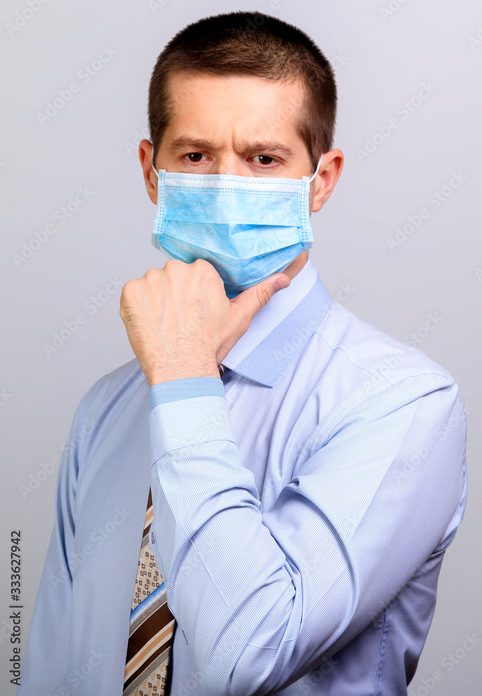 Thoughtful man in medical mask, thinks, holds hand at head
