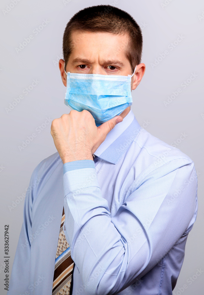 Thoughtful man in medical mask, thinks, holds hand at head Thoughtful man in medical mask, thinks, holds hand at head