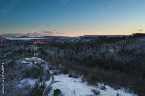 Panorama of radio antenna rising up on the top of a mountain plain above Postojna, slovenia, during early morning in winter. Visible Notranjska region in the background being lit by morning sun