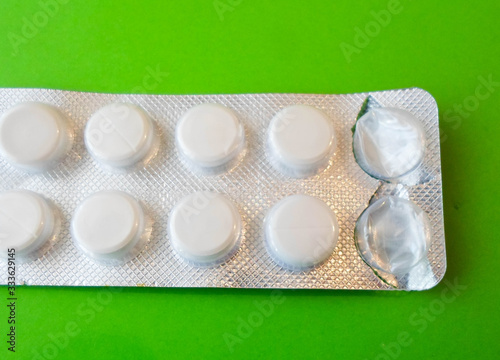 white pills on a green background. snow-white round antibiotics against viruses photo