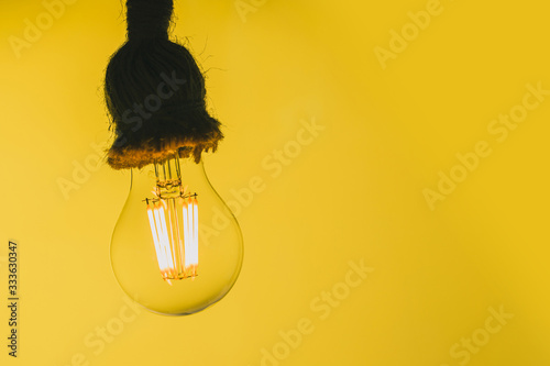 Close up view of a transparend LED light bulb resembling an old tungsten lamp on a yellow background and fluffy socket. photo