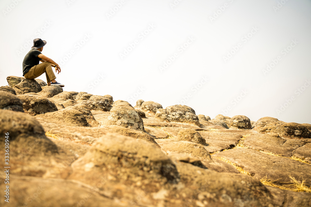 Travel man tourist sitting alone on the edge cliff mountains and looking on the valley. 