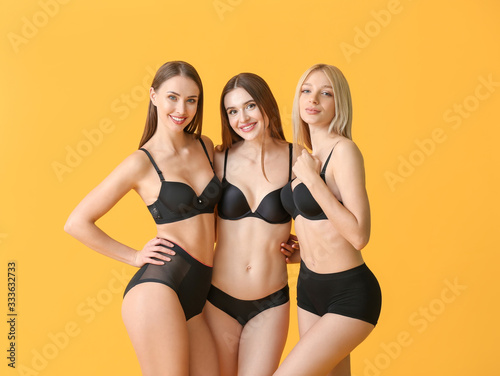 Beautiful young women in underwear on color background
