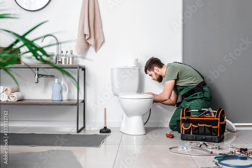 Plumber installing toilet b...