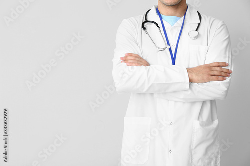 Young male doctor on light background