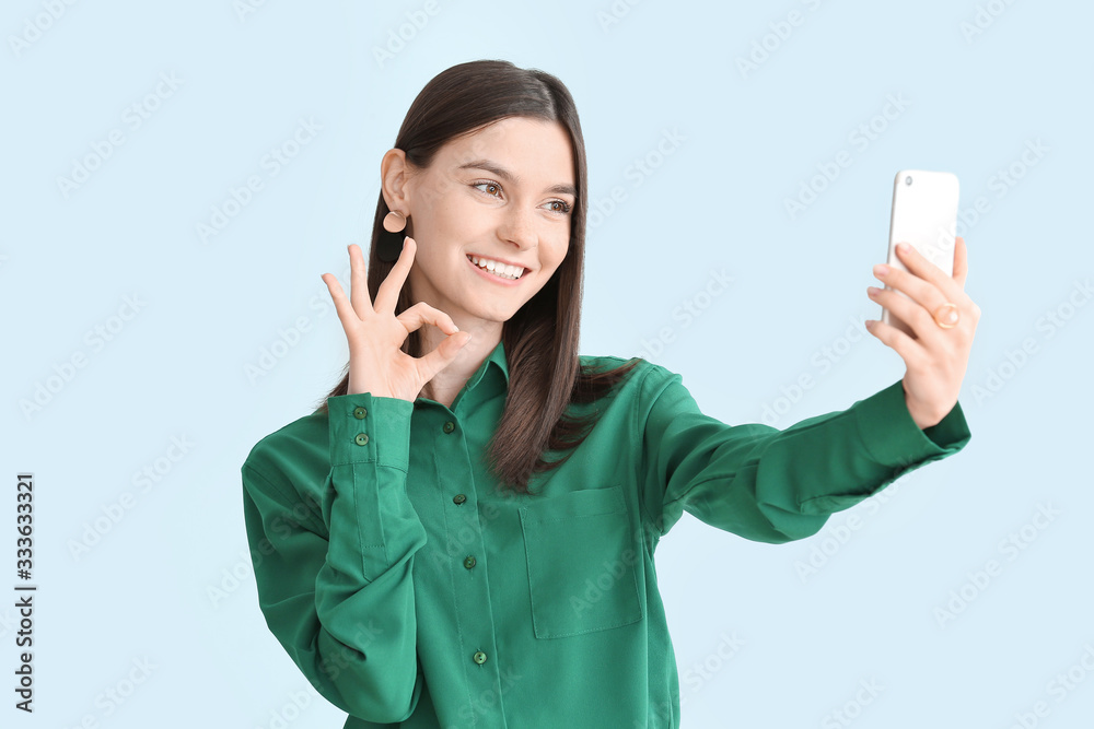 Beautiful young woman taking selfie on color background Beautiful young woman taking selfie on color background