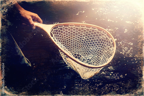 Male brook trout in a landing net, old photo effect.