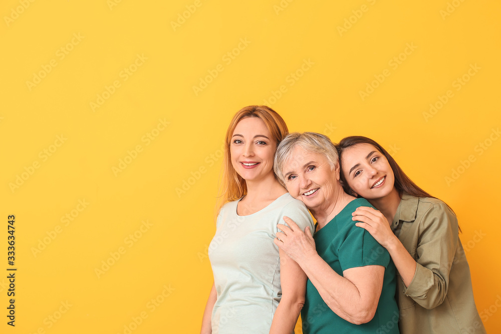 Portrait of mature woman with her adult daughter and mother on color background