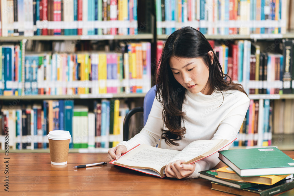 Young beautiful asian student girl working a book, learning in college library in university Young beautiful asian student girl working a book, learning in college library in university