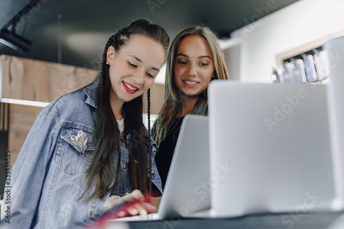 young attractive girls in an electronics store use a laptop at an exhibition. concept of buying gadgets.