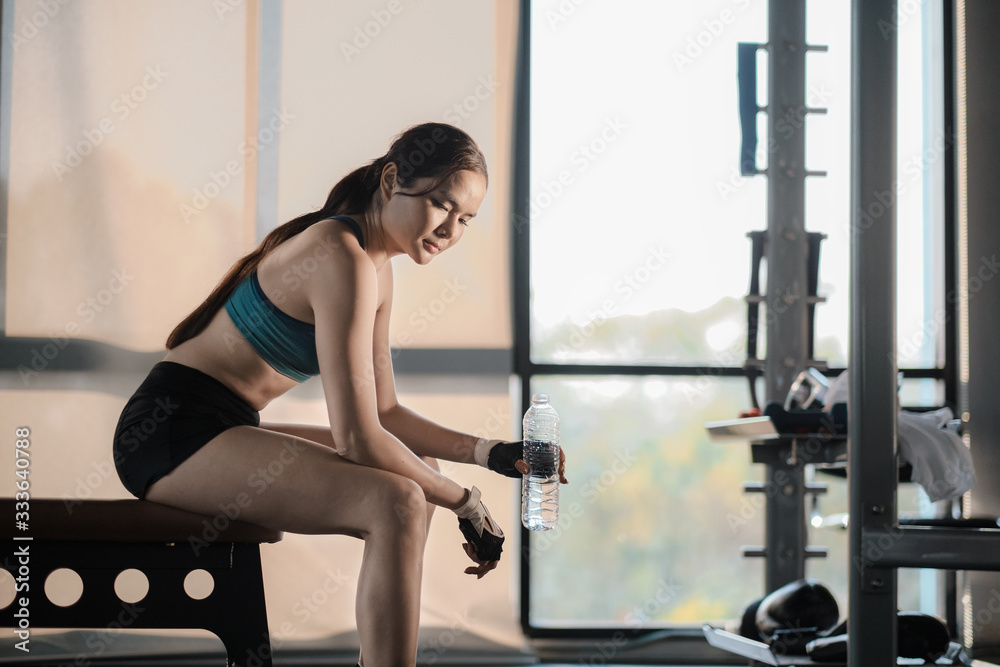 Fototapeta premium Young athletic woman drink water and rest in gym. Refreshing in gym