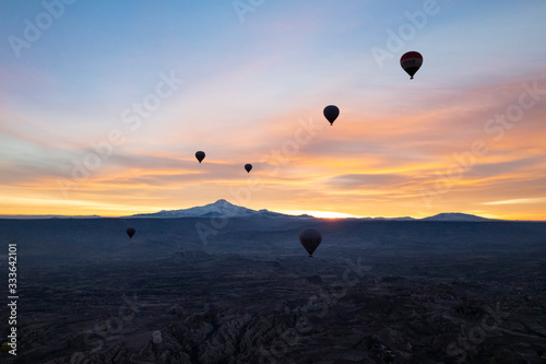 View of a volcano Mount Kayseri and silhouette of balloons seen from Goreme, Cappadocia with beautiful sunrise and colourful, golden, orange, pink and blue sky. It's fun, excited and impress activity 