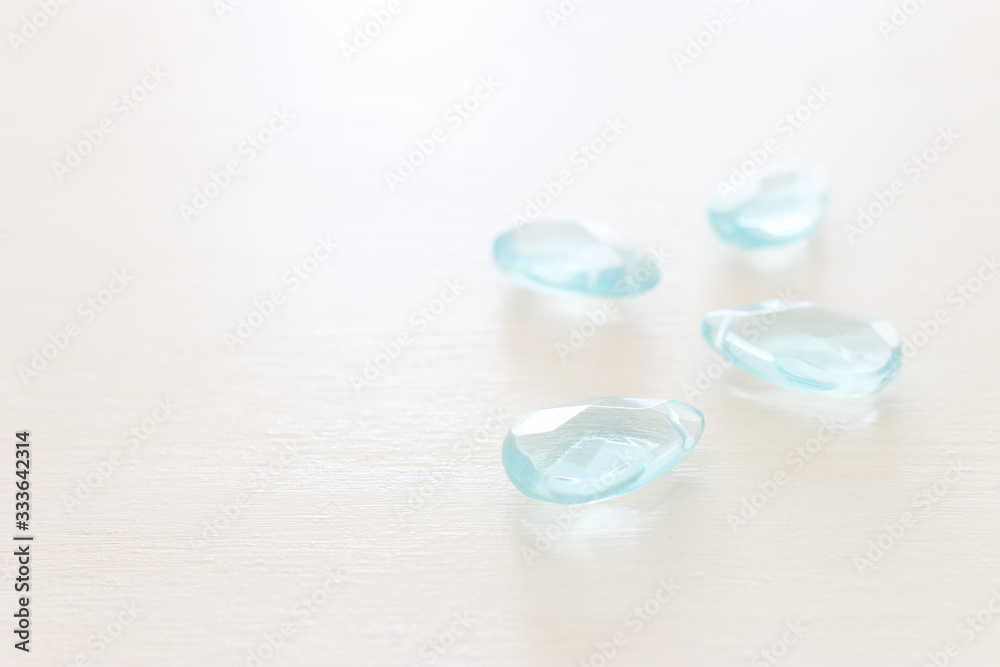 Delicate blue gemstones beads on white wooden background Delicate blue gemstones beads on white wooden background