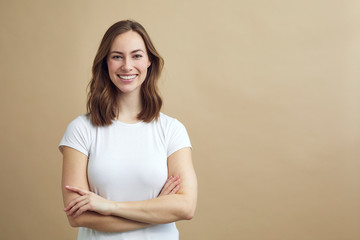 Portrait of beautiful and confident woman crossing her arms and smiling to the viewer on a modern color background with copy space