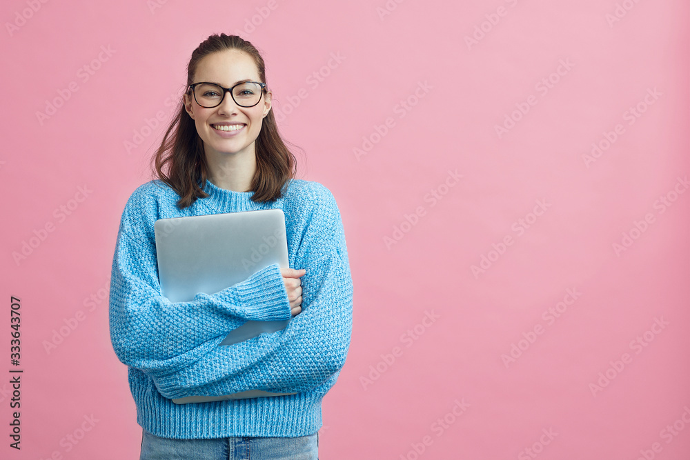 Cute looking student holding her laptop beside copy space  - obrazy, fototapety, plakaty 