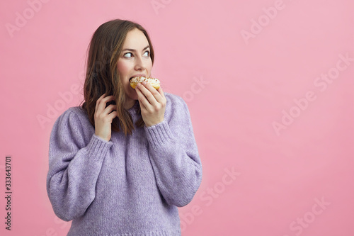 Fotobehang Pretty girl is eating a cake, and looking to se if anyone i seing her