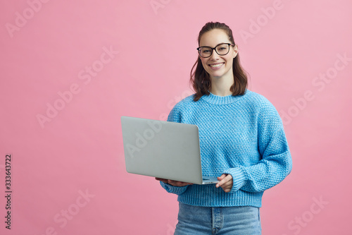 Portrait of smart looking student with glasses, holding her laptop