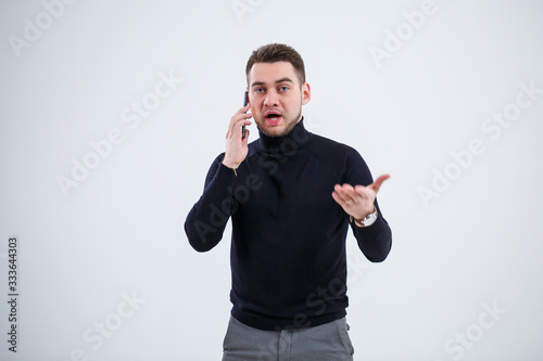 Serious guy businessman in black clothes finds out important questions by phone. Working day concept