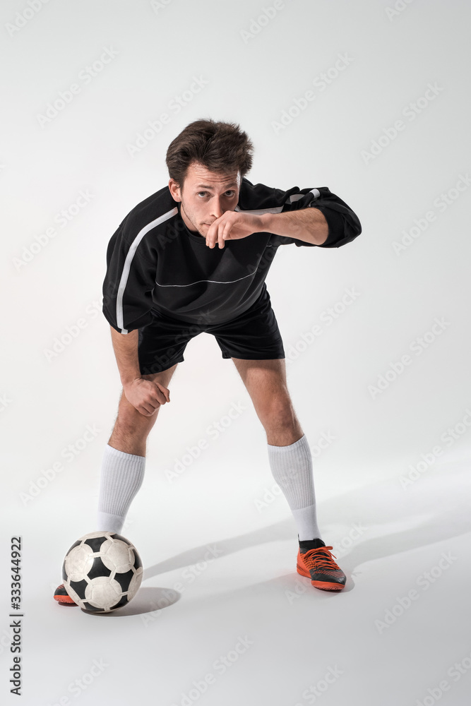 Confident soccer player in a black sportswear mops face after training.