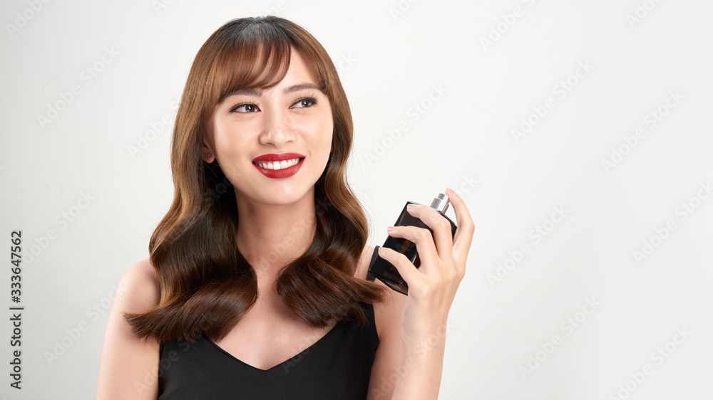 Asian girl with perfume, young woman applying perfume on her wrist and smelling Asian girl with perfume, young woman applying perfume on her wrist and smelling