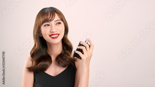 Asian girl with perfume, young woman applying perfume on her wrist and smelling