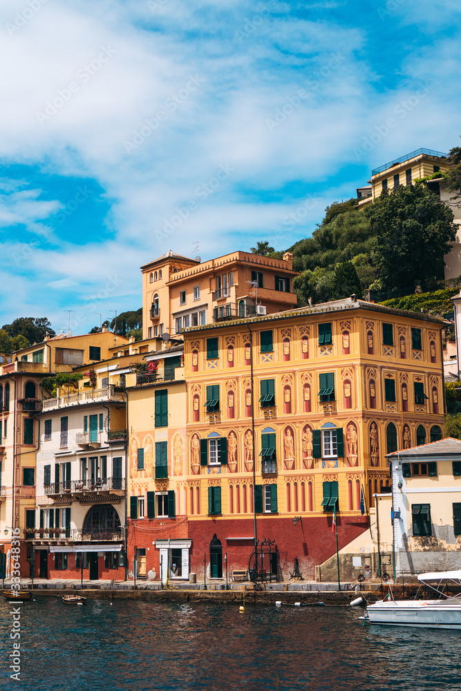 Stunning panoramic view of Portofino, one of the world’s most beautiful seaside towns on the Italian Riviera. Mediterranean landscape of yacht-filled harbor and colorful buildings on a sunny day.