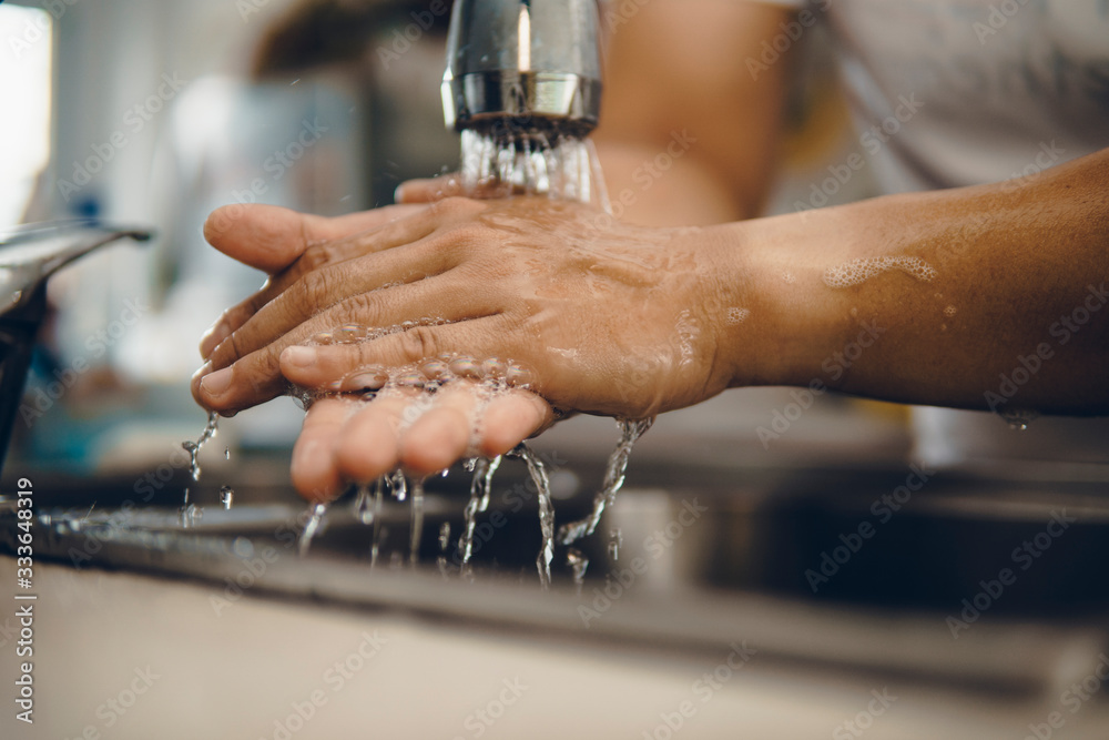 Cropped shot of an unrecognizable man washing his hands at home to prevent spreading of the coronavirus ( Covid-19) Cropped shot of an unrecognizable man washing his hands at home to prevent spreading of the coronavirus ( Covid-19)