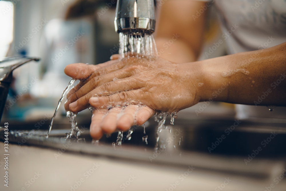 Cropped shot of an unrecognizable man washing his hands at home to prevent spreading of the coronavirus ( Covid-19) Cropped shot of an unrecognizable man washing his hands at home to prevent spreading of the coronavirus ( Covid-19)