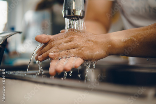 Cropped shot of an unrecognizable man washing his hands at home to prevent spreading of the coronavirus ( Covid-19)
