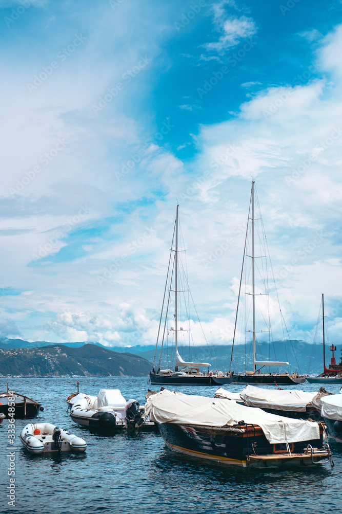 Stunning panoramic view of Portofino, one of the world’s most beautiful seaside towns on the Italian Riviera. Mediterranean landscape of yacht-filled harbour and mountains in the background.