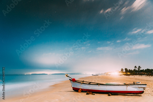 Fototapeta Naklejka Na Ścianę i Meble -  Goa, India. Real Night Sky Stars. Natural Starry Sky Blue Color Above Sea Seascape Ocean Beach. Background. Parked Old Wooden Boat At Coast