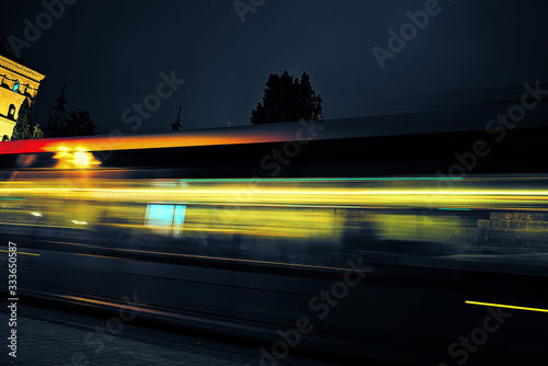 Trail of lights created by a bus driving at night through the city.